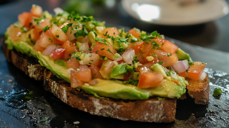 Avocado on toast, topped with diced onion and tomato