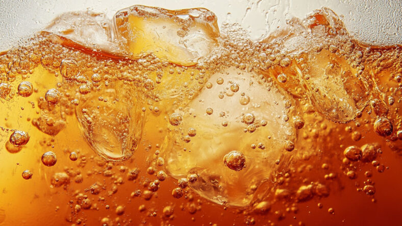 Fizzy orange soda close up with ice