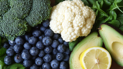 A selection of liver healthy foods, including blueberries, broccoli, and avocado.