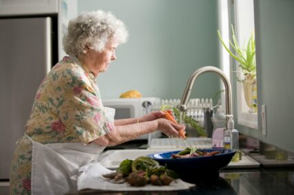 older woman washing vegetables / nutrients older adults need