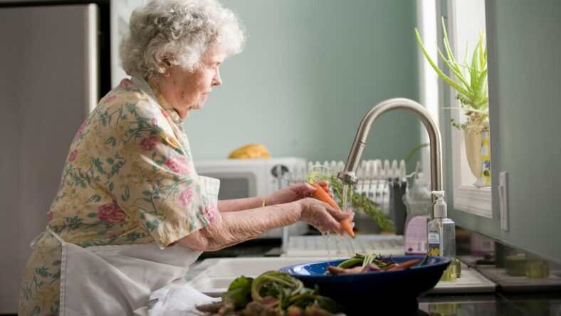 older woman washing vegetables / nutrients older adults need