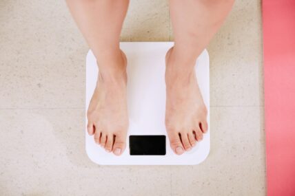 person standing on scale / myths about weight loss