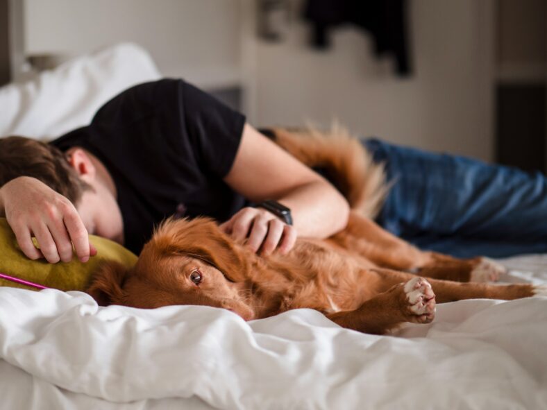 man sleeping next to dog