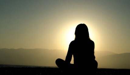 woman silhouetted by the sun / benefits of early morning meditation
