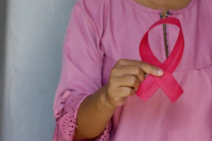 woman holding breast cancer ribbon / early signs of breast cancer