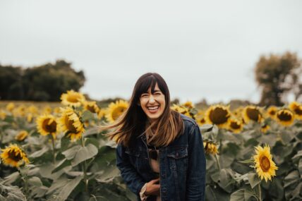 woman laughing in sunflower field / reasons to laugh more
